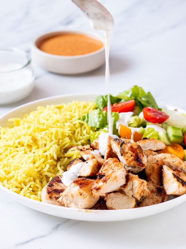 halal cart chicken and rice recipe with white sauce being poured on top