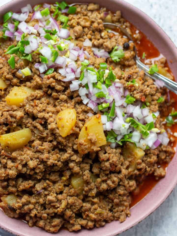 Aaloo Keema or Keema Aloo top down view garnished with onions and cilantro