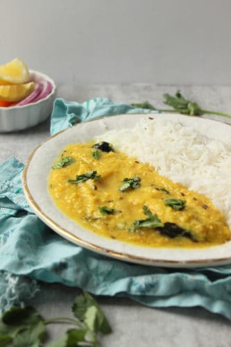 a plate of Khatti Daal with white rice and sliced red onions