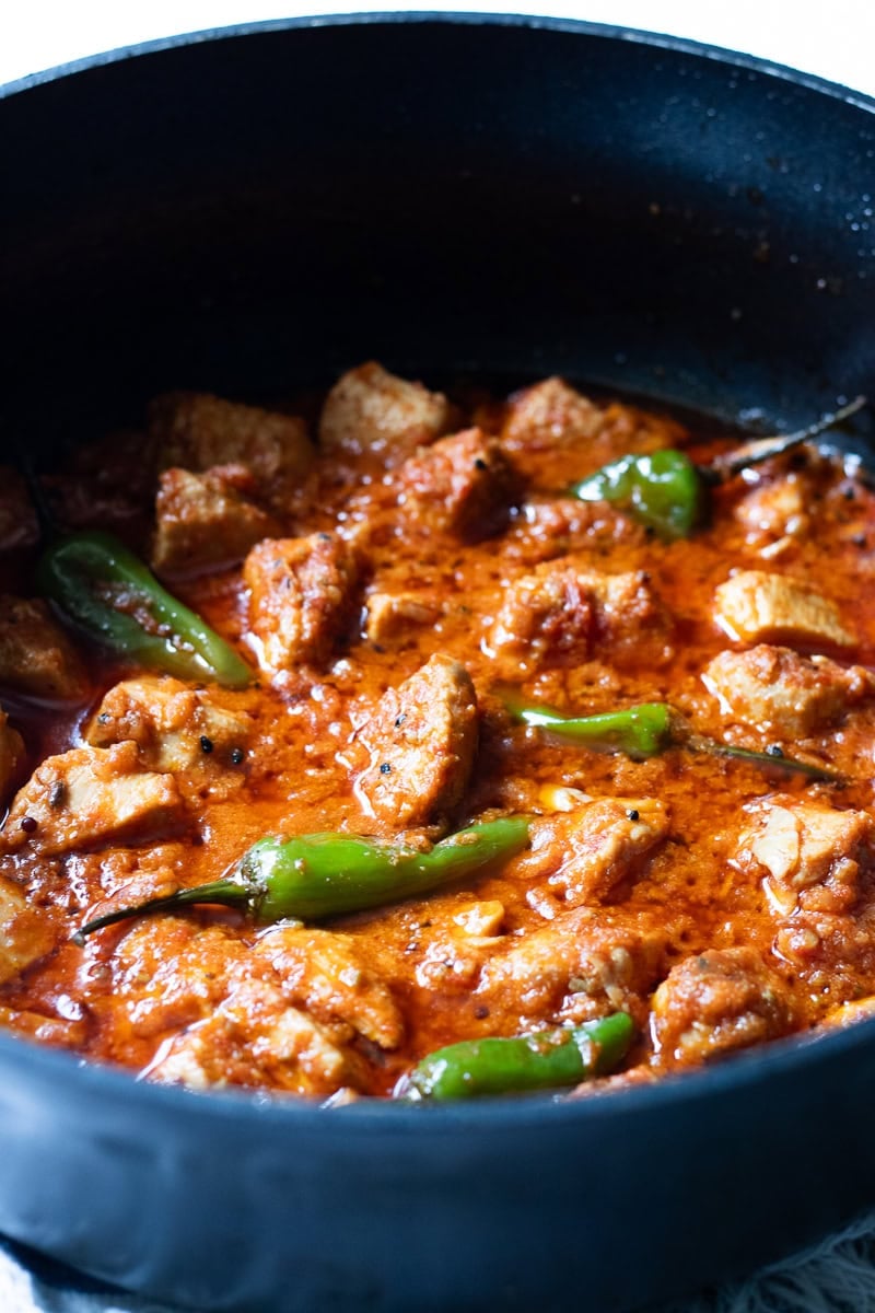 achari chicken in a black braiser 