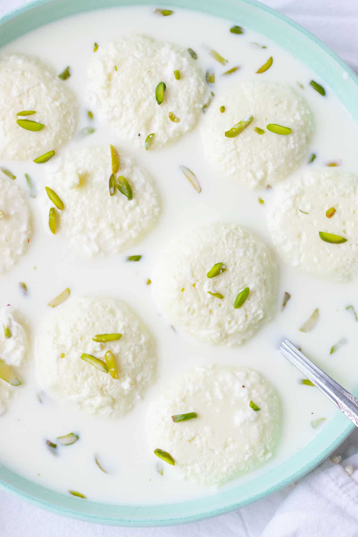 Top down view of a dish of rasmalai garnished with pistachios 