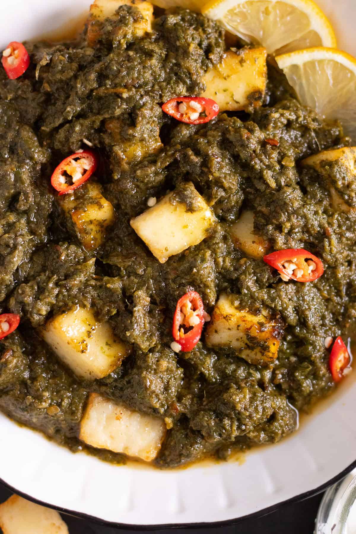 Palak paneer garnished with red chilies and a slice of lemon